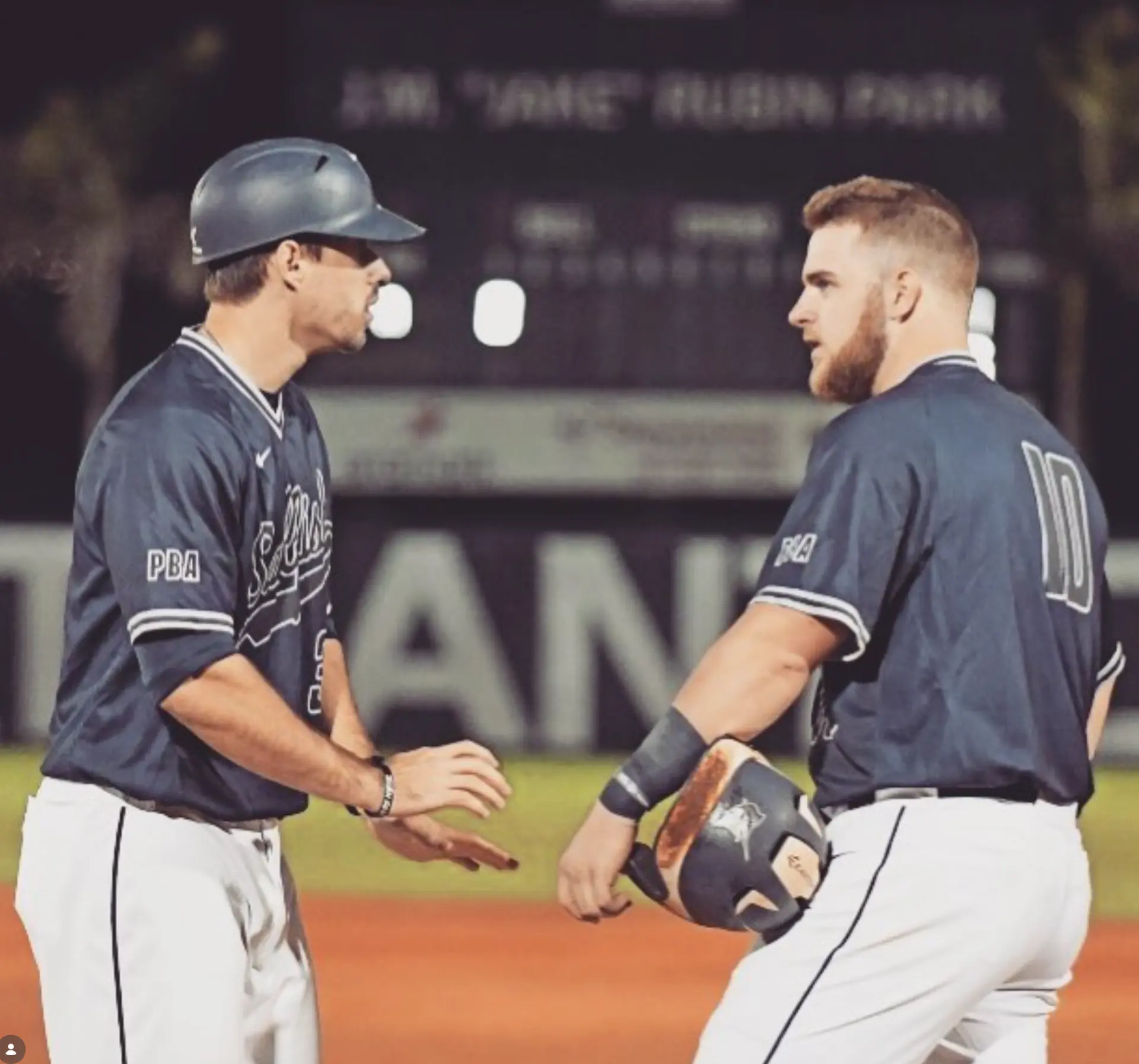 Palm Beach Atlantic players congratulating each other between bases